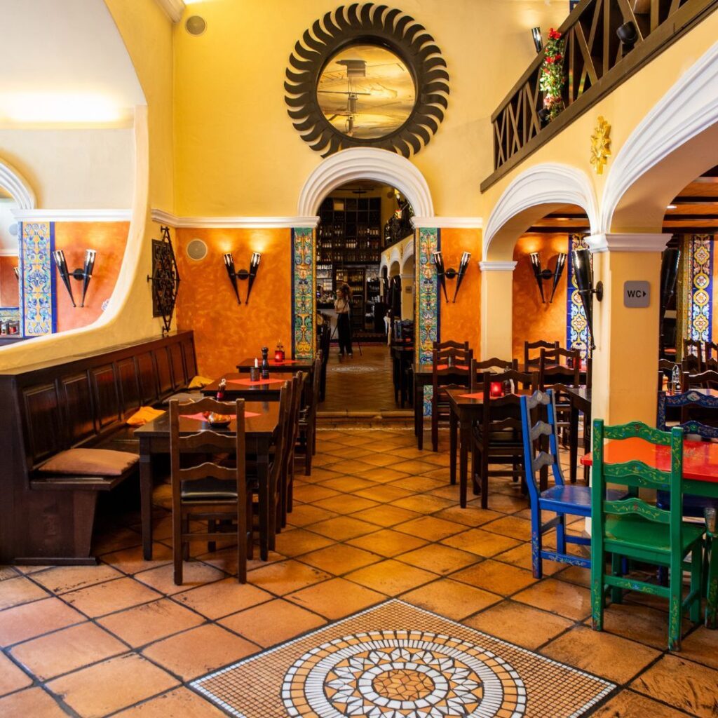 Innenraum eines spanischen Restaurants in Berlin mit bunten Stühlen, Gewölbebögen und einem Boden mit Mosaikfliesen.