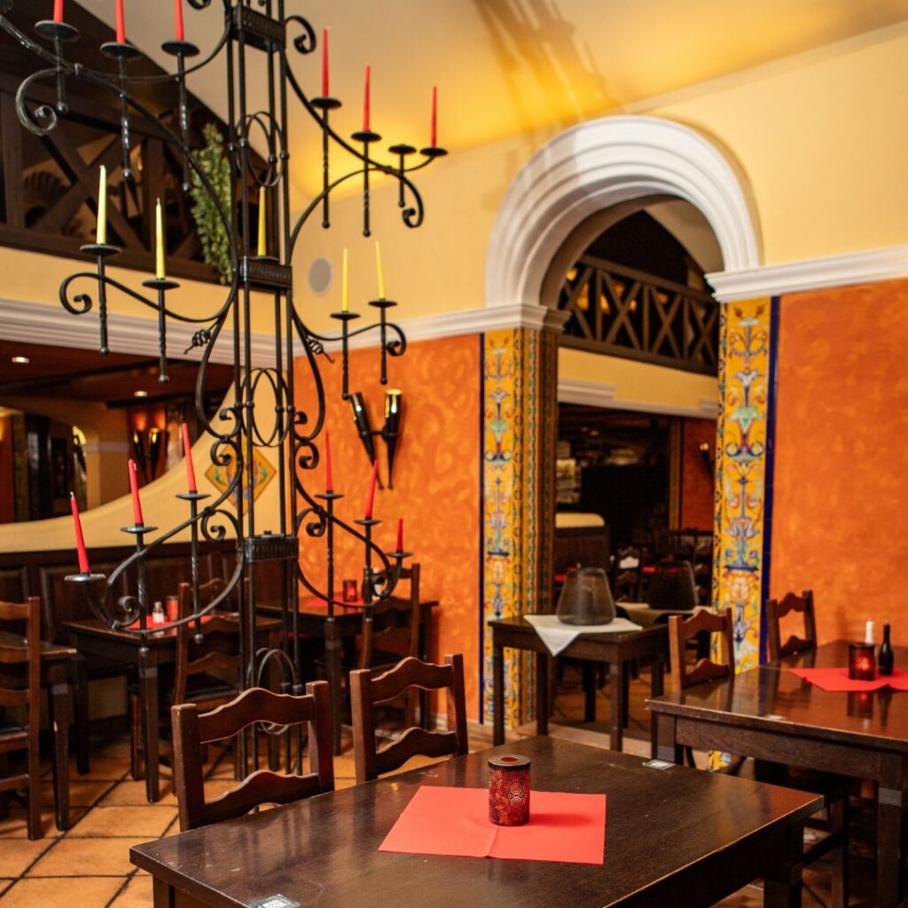 Gemütlicher Innenraum des spanischen Restaurants Vivolo Olé in Berlin mit traditioneller Dekoration, Gewölbebögen und Kerzenlicht an den Tischen.