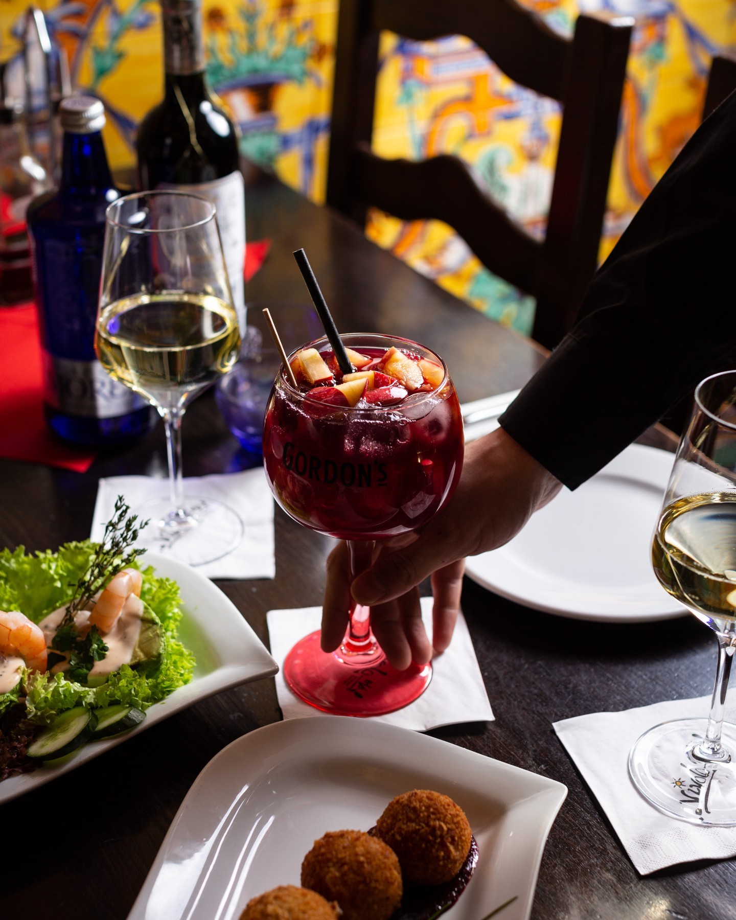 A close-up of sangria being served by a waiter at a Spanish restaurant table.