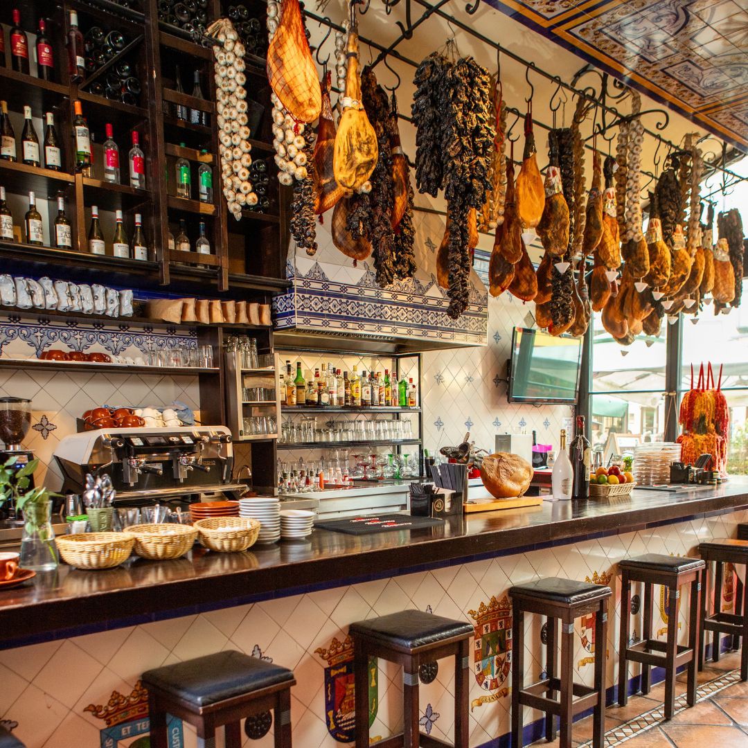 Rustikale spanische Bar mit hängendem luftgetrocknetem Schinken, Knoblauch und gefliesten Wänden.